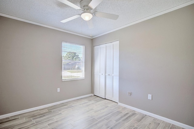 unfurnished bedroom featuring light wood finished floors, crown molding, baseboards, a closet, and a textured ceiling