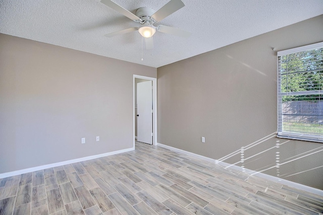 unfurnished room featuring light wood-style flooring, a textured ceiling, baseboards, and ceiling fan