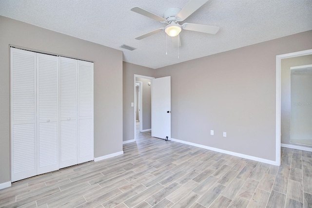 unfurnished bedroom with baseboards, visible vents, wood finish floors, a closet, and a textured ceiling