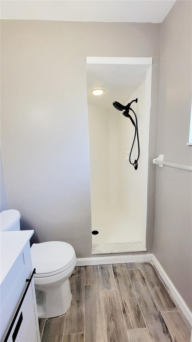 full bath featuring toilet, wood finished floors, a shower stall, baseboards, and vanity