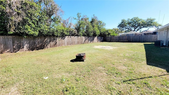 view of yard featuring cooling unit, a fenced backyard, and a fire pit