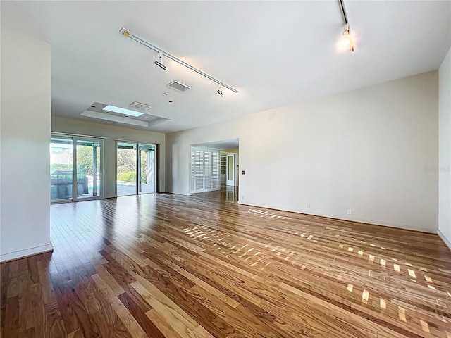 empty room featuring visible vents, track lighting, and wood finished floors