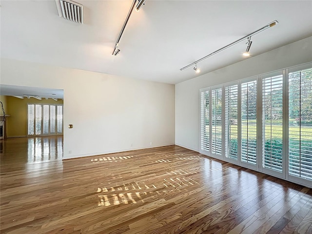 unfurnished room featuring visible vents, rail lighting, and wood finished floors