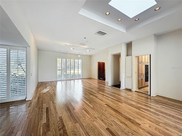 unfurnished living room with visible vents, baseboards, a skylight, recessed lighting, and light wood-style floors