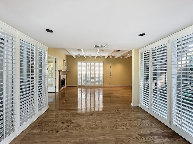 unfurnished living room with visible vents, a fireplace, baseboards, and wood finished floors