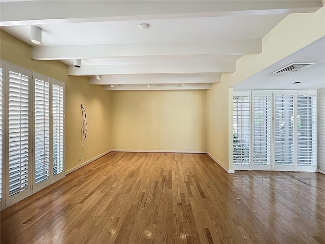 unfurnished room with beam ceiling, wood finished floors, and visible vents