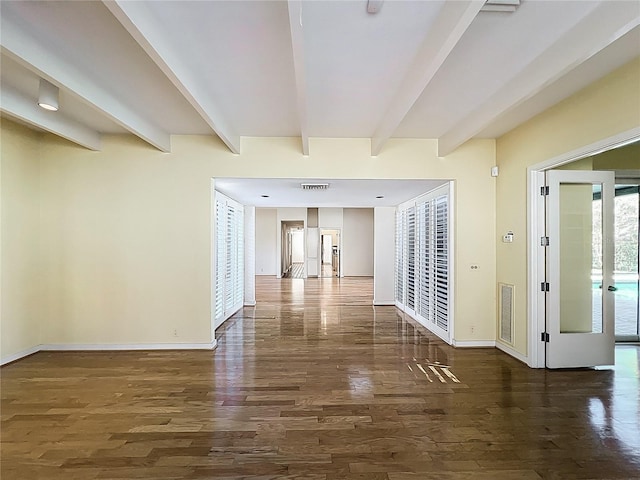 hallway with beam ceiling, wood finished floors, visible vents, and baseboards