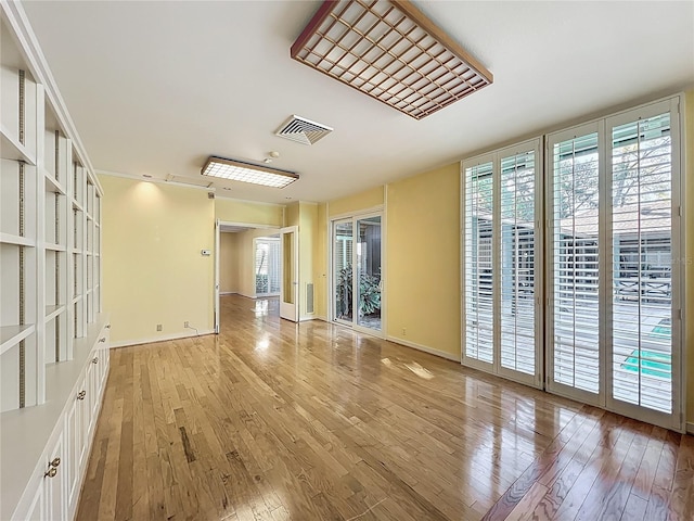 empty room featuring light wood-style flooring, a healthy amount of sunlight, and visible vents