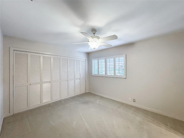 unfurnished bedroom featuring a ceiling fan, light colored carpet, a closet, and baseboards