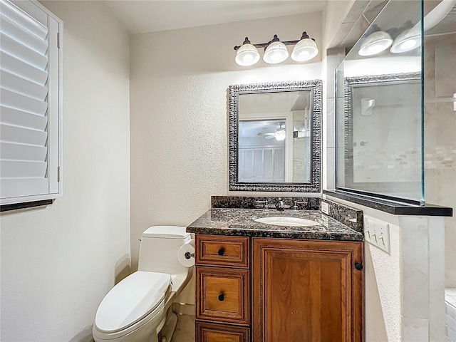 bathroom with vanity, toilet, and a textured wall