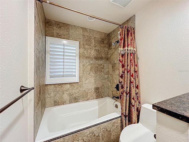 bathroom featuring toilet, visible vents, and tiled shower / bath combo