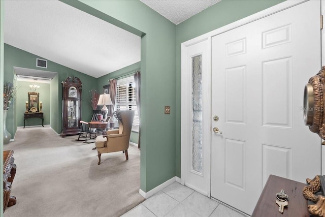 entrance foyer featuring visible vents, lofted ceiling, a textured ceiling, carpet flooring, and baseboards