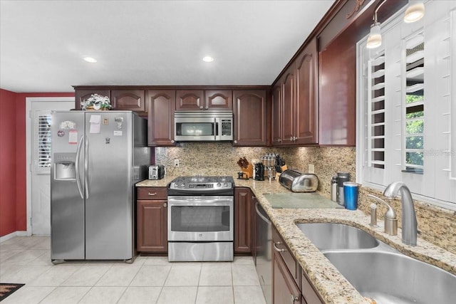 kitchen with light stone counters, backsplash, appliances with stainless steel finishes, and a sink