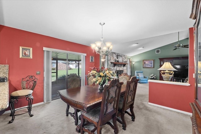 dining room featuring visible vents, ceiling fan with notable chandelier, carpet floors, a stone fireplace, and lofted ceiling