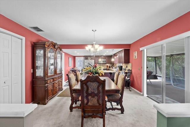 dining room with a notable chandelier, baseboards, visible vents, and light carpet