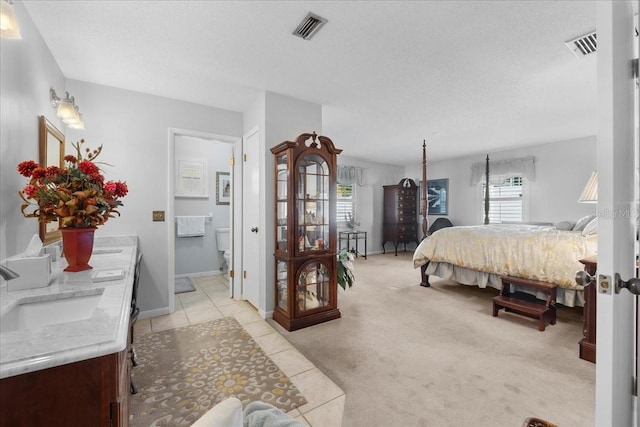 bedroom with a textured ceiling, light carpet, visible vents, and a sink