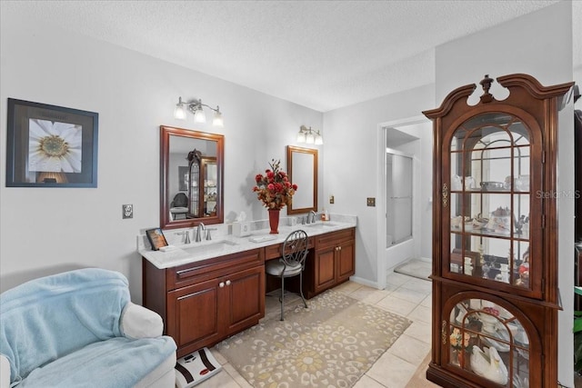 full bathroom with tile patterned floors, a shower stall, a textured ceiling, and a sink