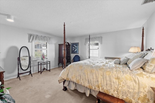 bedroom with visible vents, multiple windows, a textured ceiling, and light carpet