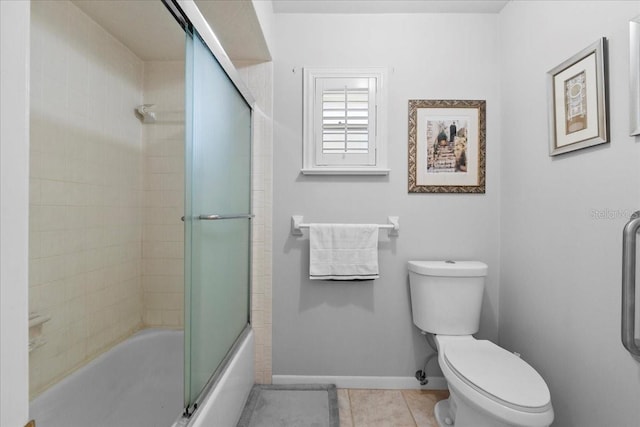 bathroom featuring tile patterned floors, enclosed tub / shower combo, baseboards, and toilet