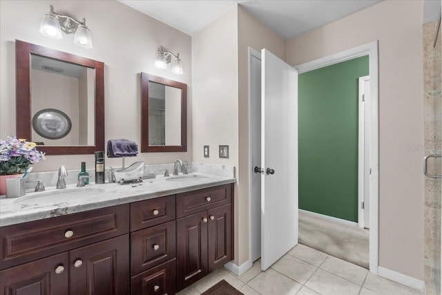 full bath with a sink, baseboards, double vanity, and tile patterned flooring