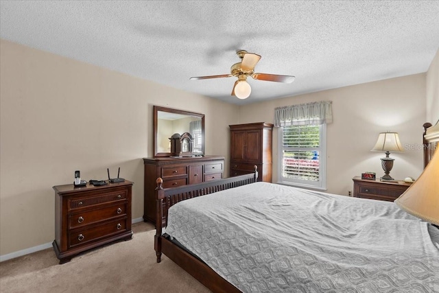 bedroom featuring light carpet, a textured ceiling, a ceiling fan, and baseboards