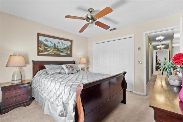 bedroom featuring baseboards, visible vents, a closet, light carpet, and ceiling fan with notable chandelier