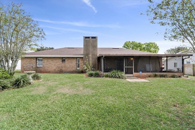 rear view of house featuring brick siding, a lawn, a chimney, and a sunroom