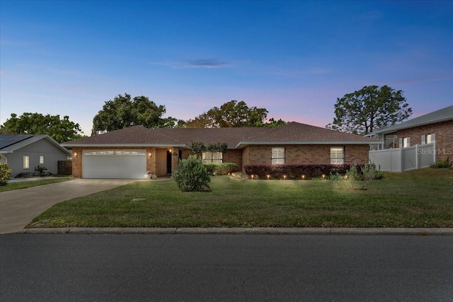 single story home featuring fence, a yard, concrete driveway, an attached garage, and brick siding