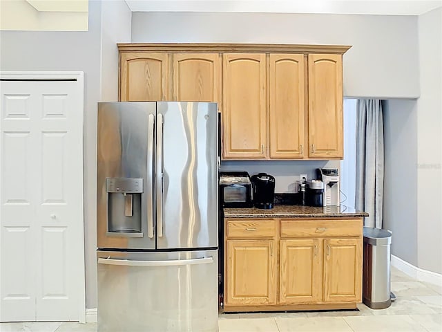 2420 Windchaser Ct, Melbourne, FL 32904 - kitchen with light brown cabinetry, dark stone counters, stainless steel fridge with ice dispenser, and baseboards