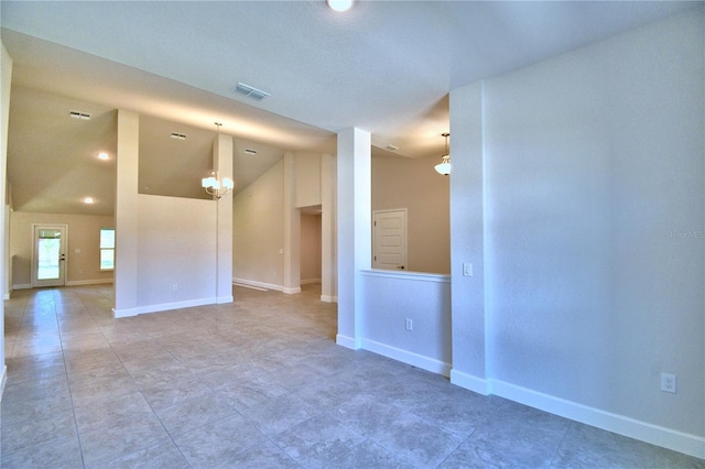 spare room with baseboards, visible vents, and vaulted ceiling