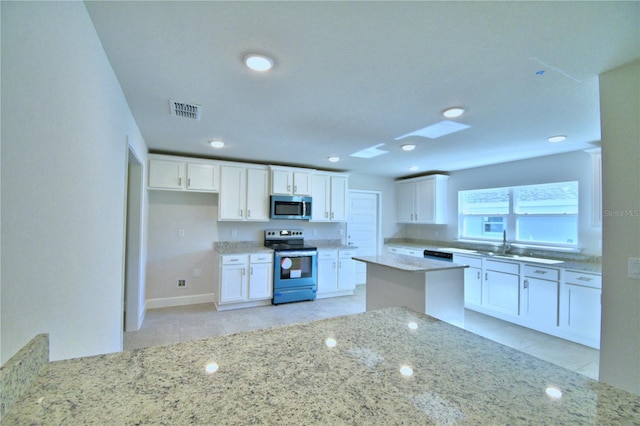 kitchen featuring white cabinets, light stone countertops, light tile patterned floors, and stainless steel appliances