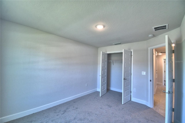 unfurnished bedroom featuring carpet floors, a textured ceiling, baseboards, and visible vents