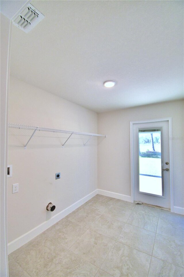 laundry area featuring light tile patterned floors, baseboards, visible vents, electric dryer hookup, and laundry area