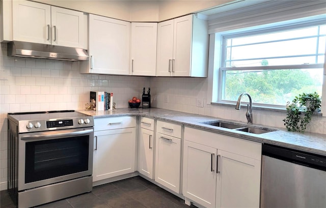 2816 Fairmount Ave, Lakeland, FL 33803 - kitchen featuring stainless steel appliances, under cabinet range hood, white cabinetry, dark tile patterned flooring, and tasteful backsplash