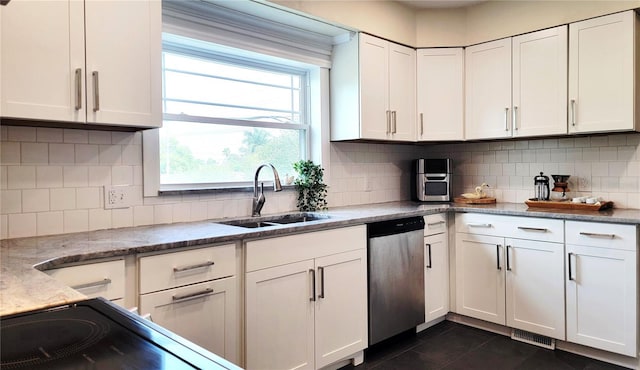 2816 Fairmount Ave, Lakeland, FL 33803 - kitchen featuring stainless steel dishwasher, dark tile patterned floors, healthy amount of natural light, and white cabinets