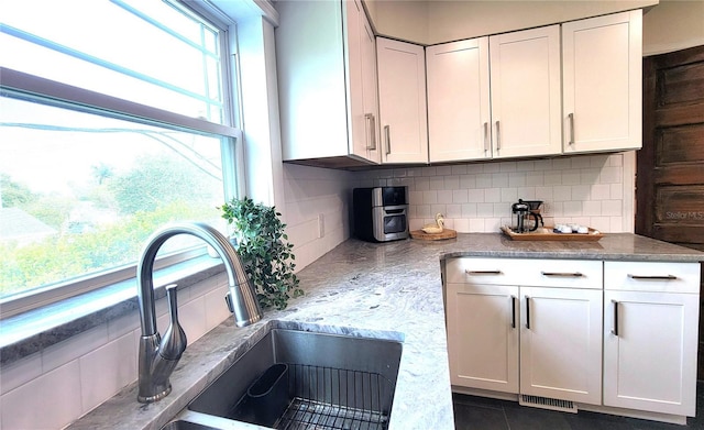 2816 Fairmount Ave, Lakeland, FL 33803 - kitchen featuring tasteful backsplash, white cabinetry, stone counters, and dark tile patterned floors