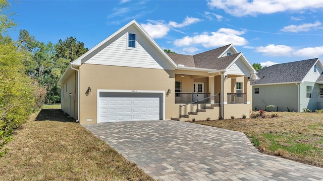 view of front of property with an attached garage, stucco siding, a front lawn, decorative driveway, and a porch