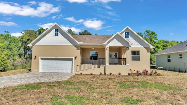 view of front of property with a front lawn, stucco siding, covered porch, and a garage