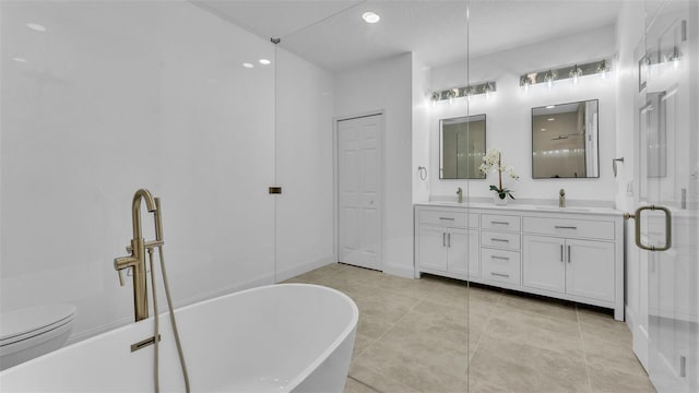 bathroom with a sink, toilet, tile patterned floors, double vanity, and a freestanding bath