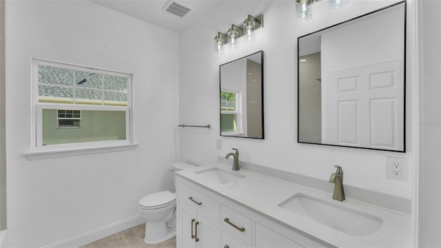 bathroom with double vanity, toilet, visible vents, and a sink