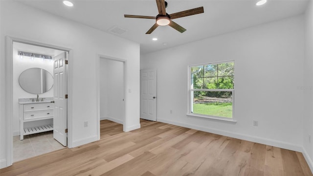 unfurnished bedroom featuring a sink, baseboards, light wood-type flooring, and visible vents
