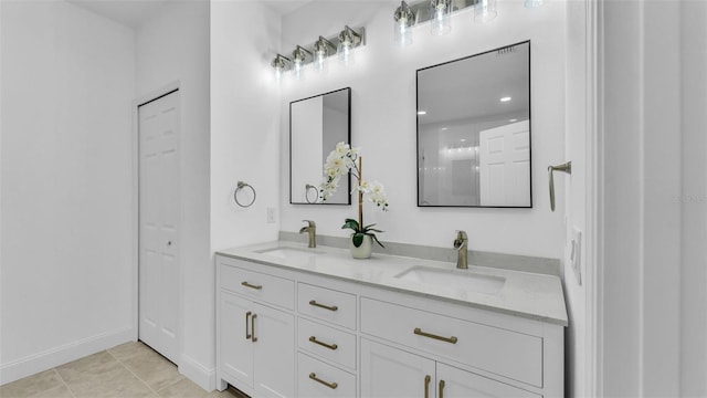 full bath with a sink, double vanity, baseboards, and tile patterned floors