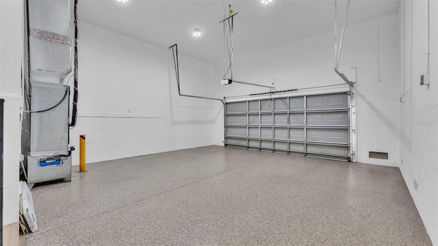 garage featuring concrete block wall and a garage door opener