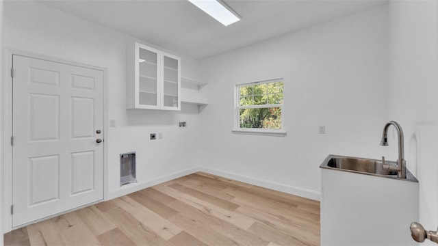 washroom with a sink, electric dryer hookup, laundry area, baseboards, and light wood-style floors