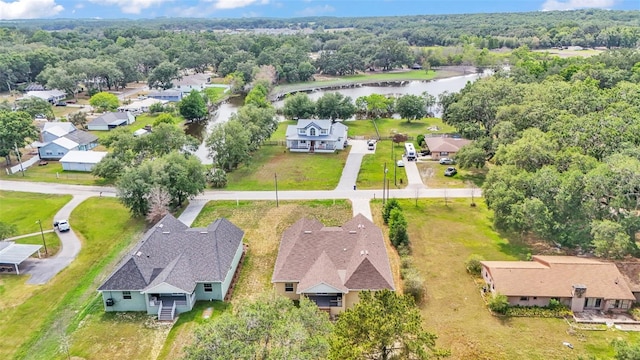 drone / aerial view with a wooded view, a water view, and a residential view