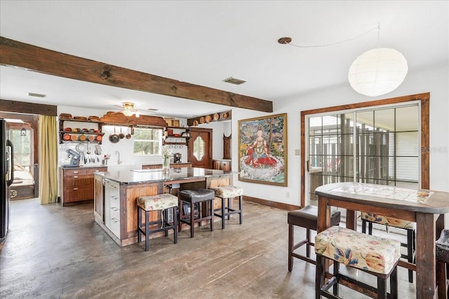 8922 Pritcher Rd, Lithia, FL 33547 - kitchen featuring a kitchen bar, baseboards, beamed ceiling, a kitchen island with sink, and open shelves