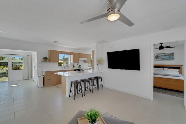 kitchen featuring decorative backsplash, a kitchen breakfast bar, a ceiling fan, a peninsula, and light countertops
