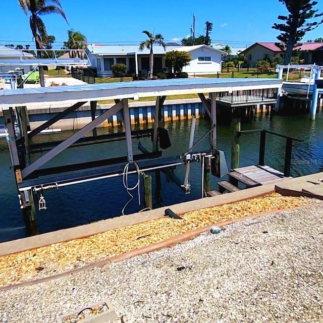 view of dock with a water view, a residential view, and boat lift
