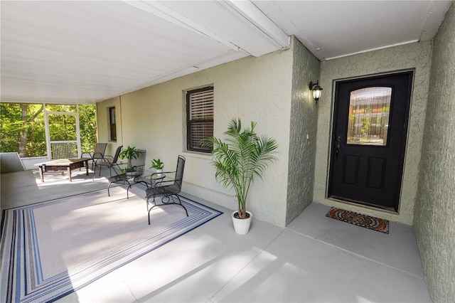 view of exterior entry with covered porch and stucco siding