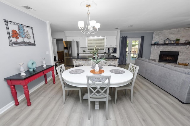 dining area with an inviting chandelier, crown molding, light wood finished floors, and visible vents